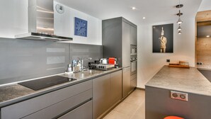 A modern kitchen with grey cabinetry, stainless steel appliances, and a built-in oven.