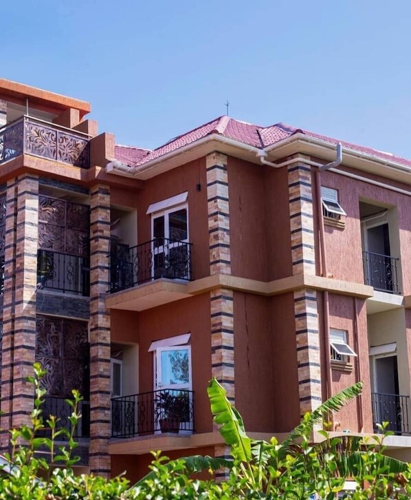 A multi-story residential building with balconies, a flat roof, and a brick facade.