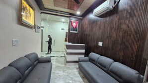 A reception area with a wooden wall, a reception desk, and two grey sofas. - RK Residency (Vrindavan)