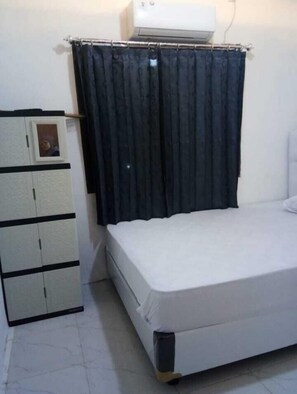 Ein Schlafzimmer mit einem Bett, einem Kleiderschrank und einem Vorhang.