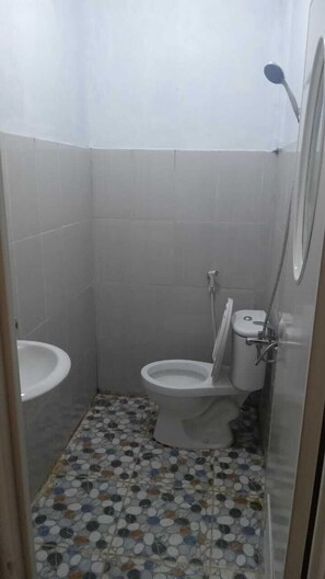 Ein kleines Badezimmer mit Toilette, Bidet und Waschbecken. Der Boden ist mit einem Mosaikfliesenmuster versehen.