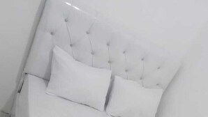 A white bed with a tufted headboard and two pillows.