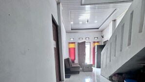 A hallway with a tiled floor, a sofa, and a staircase.