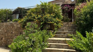 A stone staircase leading to a house with a stone wall and a metal fence. - Villa daisy, Chia (Sardegna)