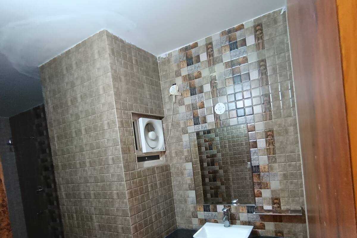 Un baño con pared de azulejos, un lavamanos y un inodoro.