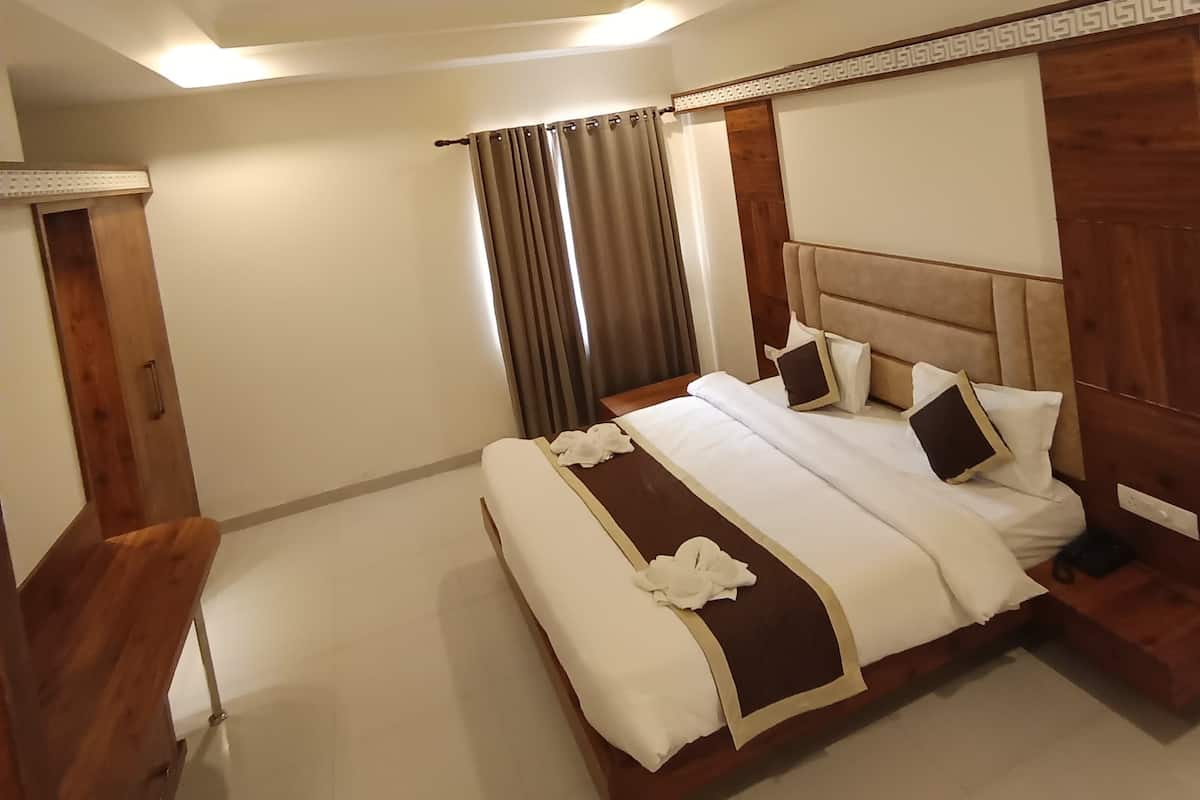 Una habitación de hotel con una cama grande, cabecera de madera y un ventilador de techo.