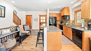 Una cocina moderna con armarios de madera, microondas integrado y refrigerador de acero inoxidable.