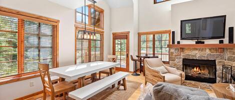 A spacious living area with a fireplace, a television, and a dining area with wooden furniture.