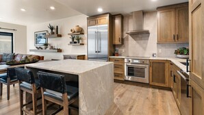 Una cocina moderna con armarios de madera, un refrigerador de acero inoxidable e una isla de mármol.