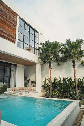 Een modern huis met twee verdiepingen, een zwembad, grote ramen en een balkon.