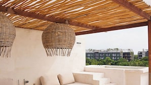 A rooftop terrace with a wooden pergola, a sofa set, and a dining table. - Arrova Bali Berawa, Canggu by Sandara (Jimbaran)