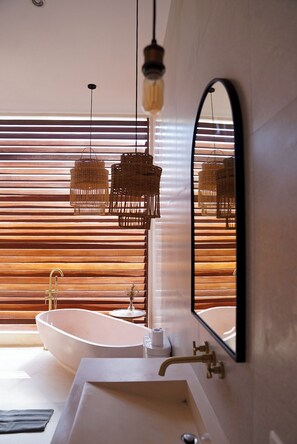 A modern bathroom with a freestanding bathtub, a sink, and a mirror.