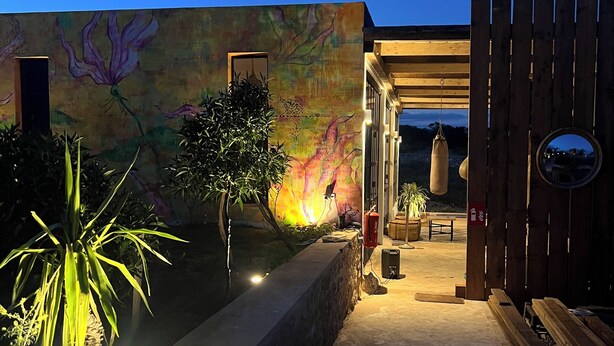 A modern outdoor area with a concrete pathway, a wooden pergola, and a mural on the wall. - The Ocean Breeze bungalow (Sidi Kaouki)