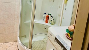 Une salle de bain moderne avec une douche à parois de verre, des toilettes intégrées et un lave-linge.