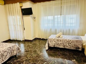 A hotel room with two beds, a flat-screen TV mounted on the wall, and a window with sheer curtains. - Cozy stay (Mestre)