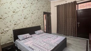 A bedroom with a bed, a nightstand, a wardrobe, a ceiling fan, and patterned wallpaper.