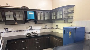 A kitchen with dark wooden cabinets, a blue refrigerator, and a gas stove.