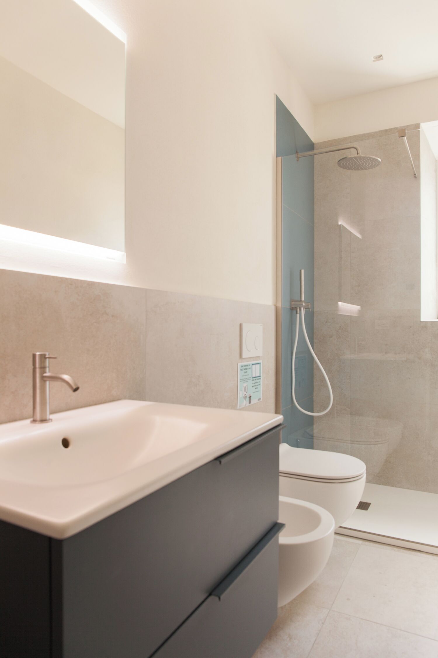 Un bagno moderno con lavandino ampio, toilette e cabina doccia in vetro.