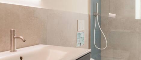 Un bagno moderno con lavandino ampio, toilette e cabina doccia in vetro.