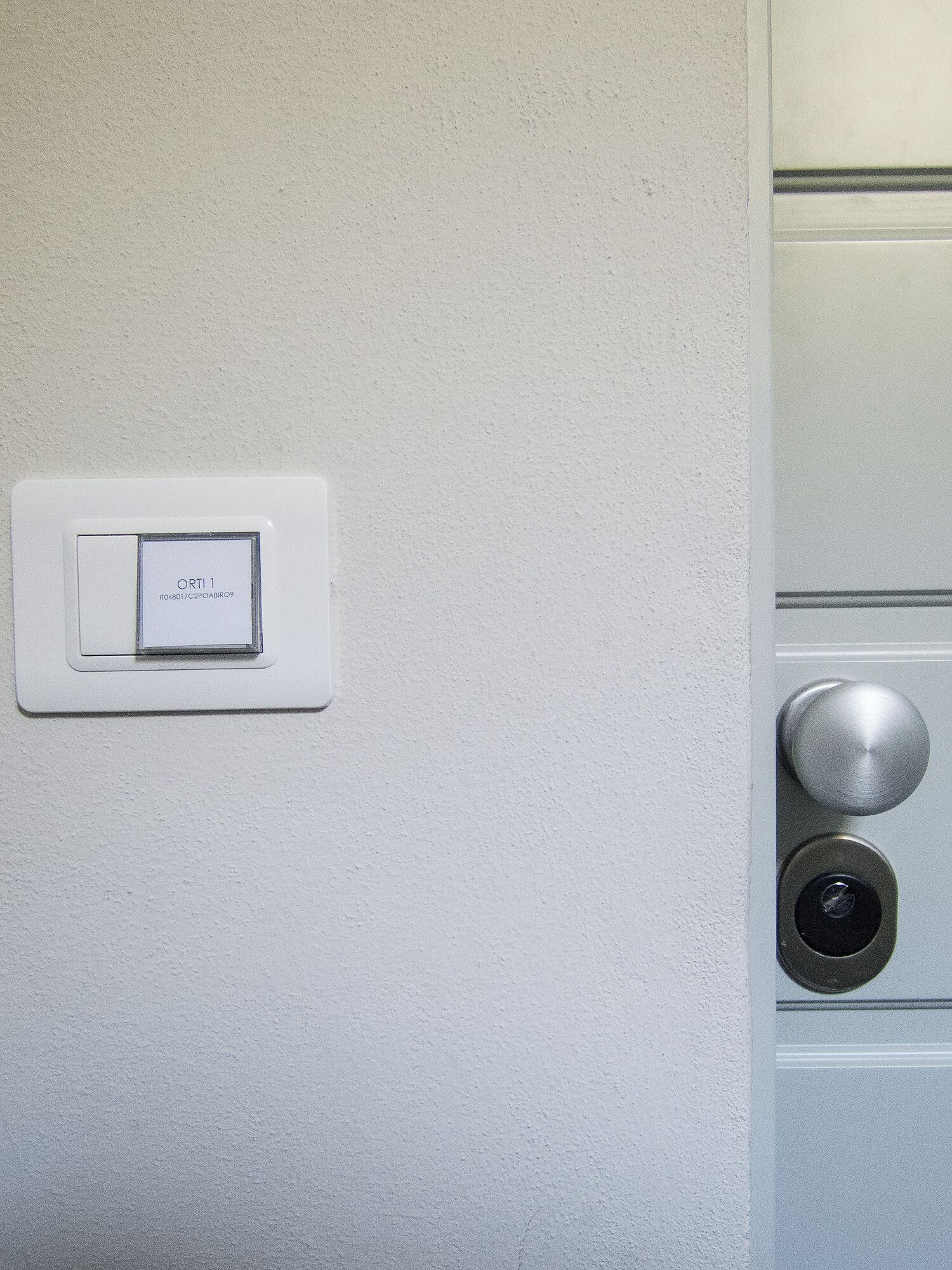 Un mur blanc avec un interrupteur et une poignée de porte.