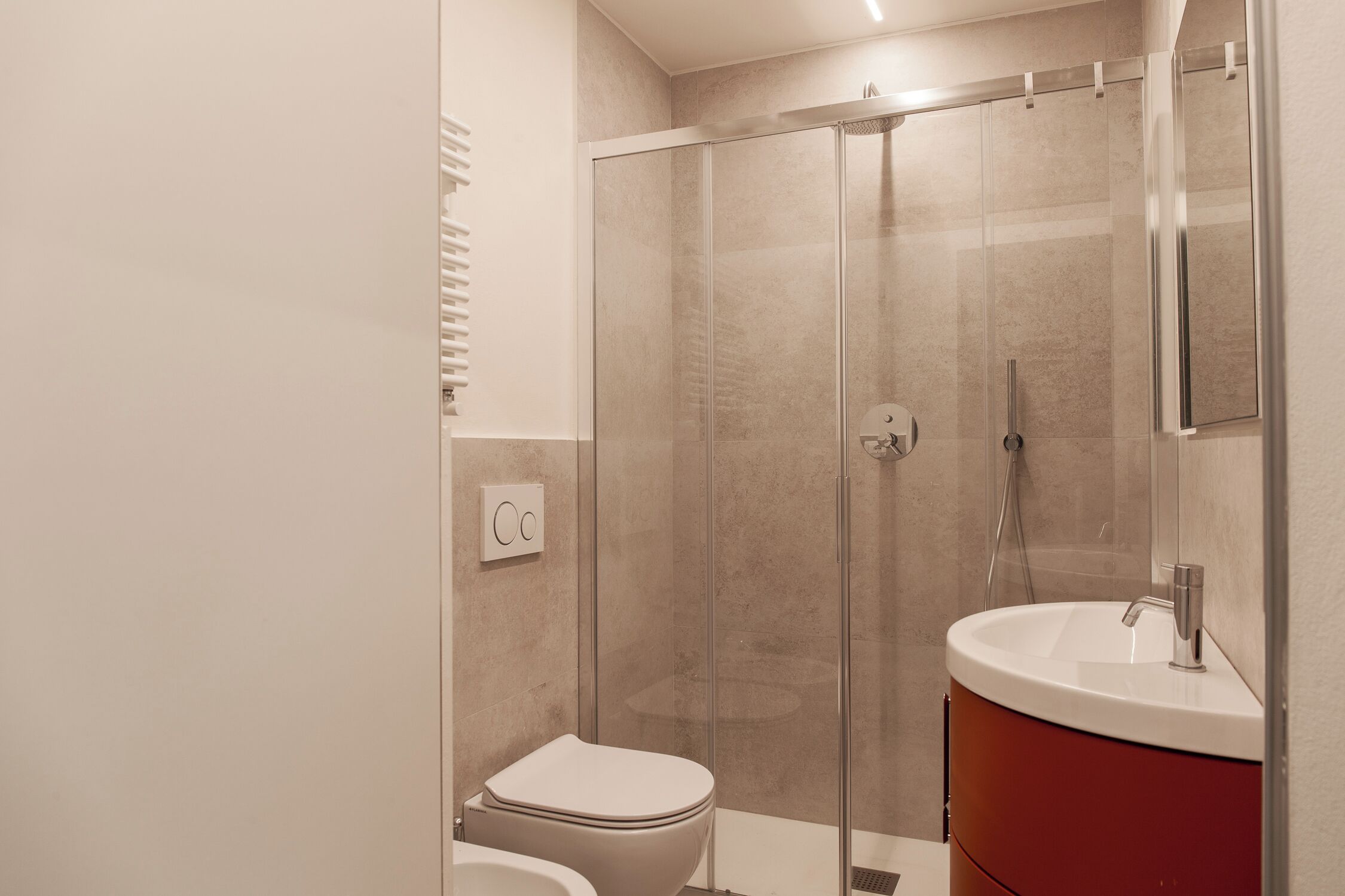 Een moderne badkamer met een glazen douchecabine, een wit toilet en een wastafel met spiegel.