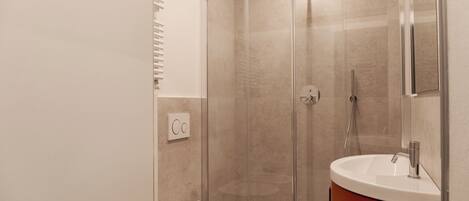 A modern bathroom with a glass-enclosed shower, a white toilet, and a vanity with a mirror.