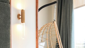 A bed with a hanging chair, a wall-mounted light fixture, and a window with curtains. - Hospedium Hotel A Mar (Villafranca de los Barros)
