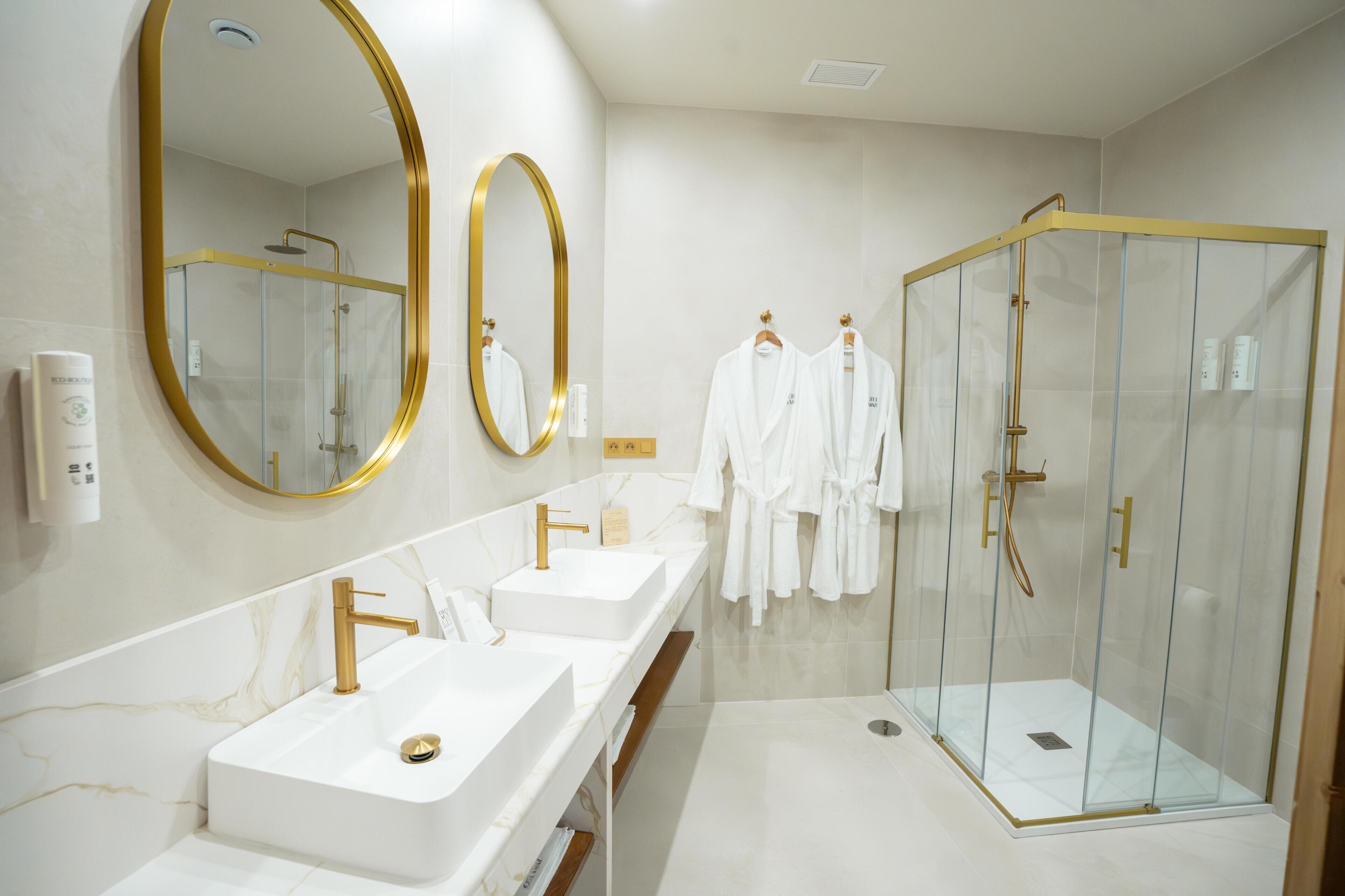 Une salle de bain moderne avec un grand miroir, deux lavabos et une douche à parois de verre.