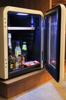 Un refrigerador pequeño con una variedad de bebidas y aperitivos en su interior.