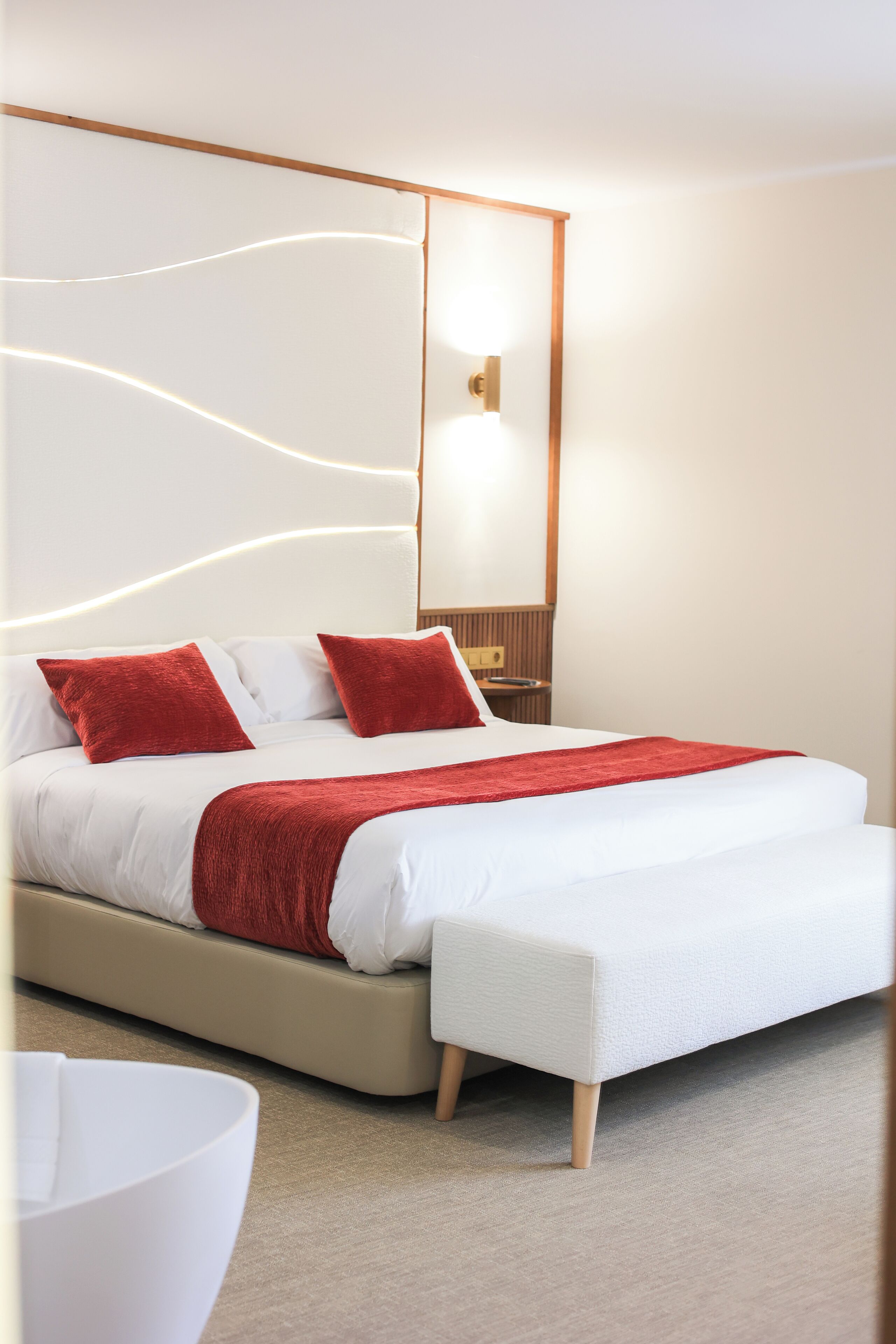 Ein modernes Schlafzimmer mit einem großen Bett, roten Kissen und einem Nachttisch.