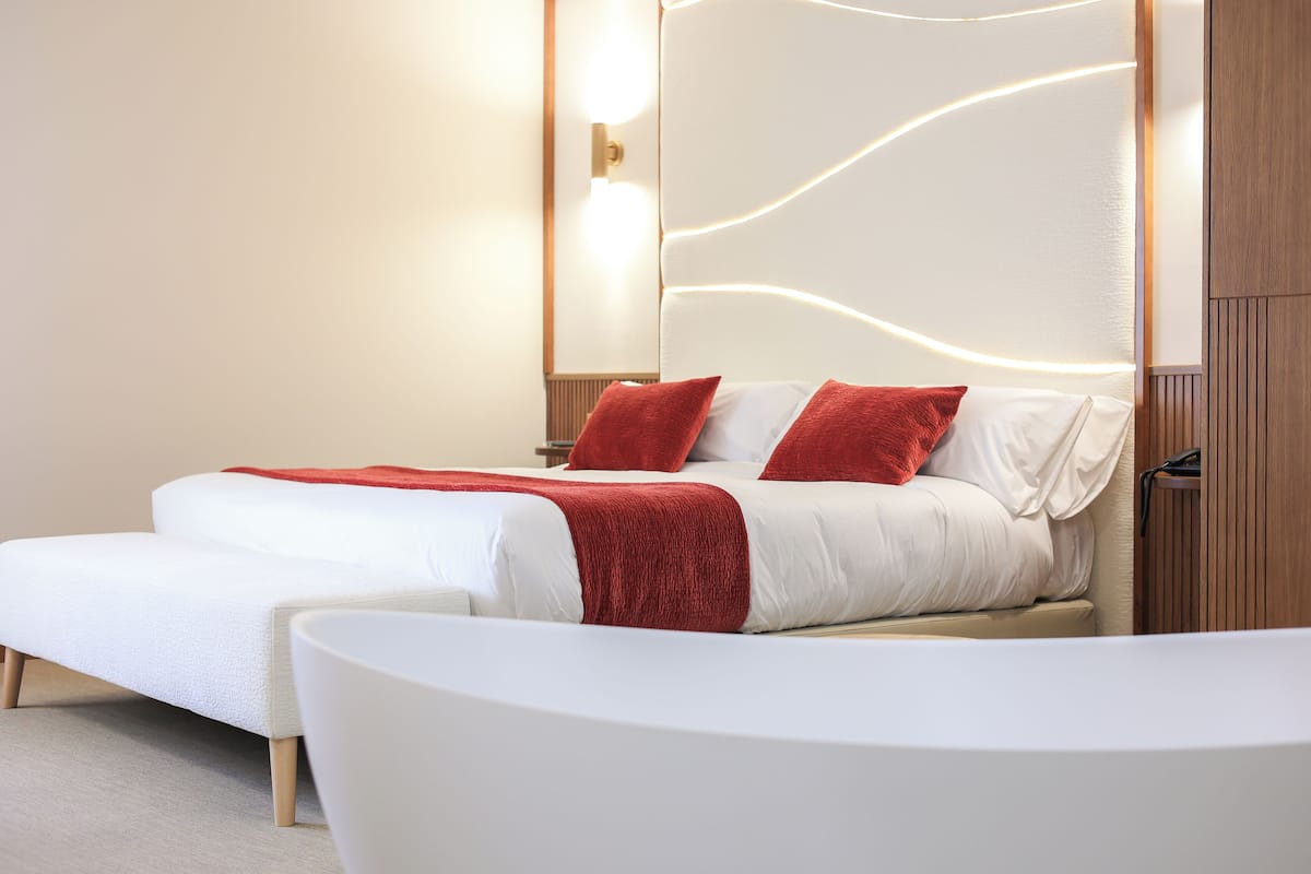 Ein modernes Hotelzimmer mit einem großen Bett, einer separaten Sitzecke und einer Wandpaneele aus Holz.