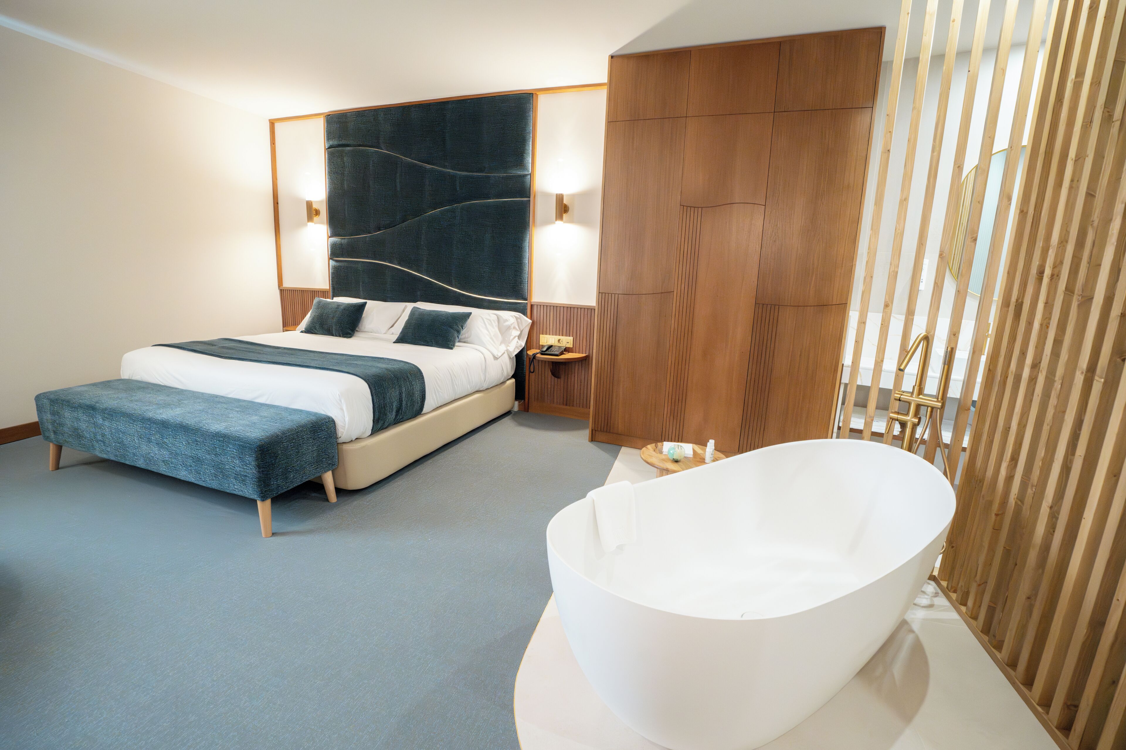 Una habitación de hotel moderna con una cama grande, una bañera blanca y paneles de madera.