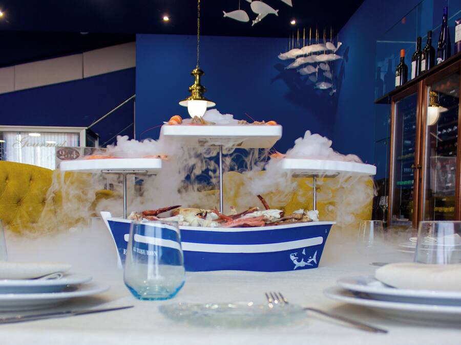 A dining table set with plates, cutlery, and a centerpiece featuring a seafood display.