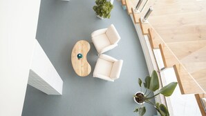 A modern interior with a grey floor, white walls, a wooden staircase, and a seating area with two white chairs and a wooden coffee table. - Hospedium Hotel A Mar (Villafranca de los Barros)