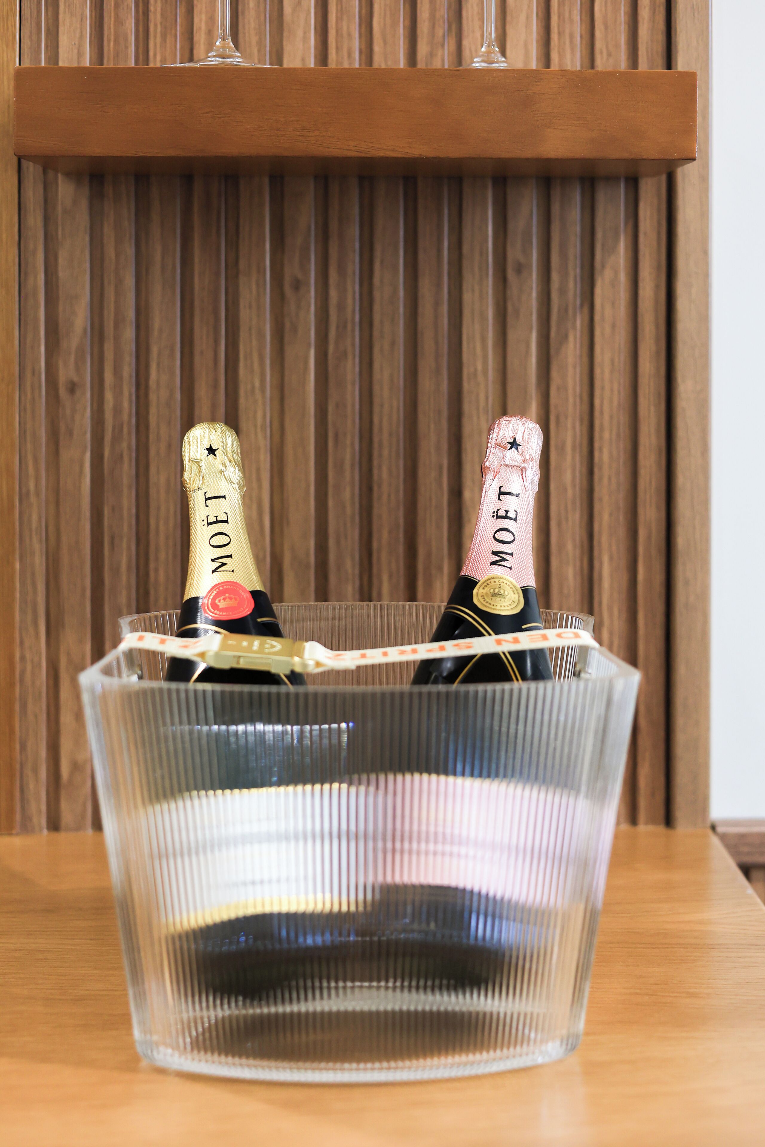 Un balde de hielo de vidrio transparente con dos botellas de champán Moët.
