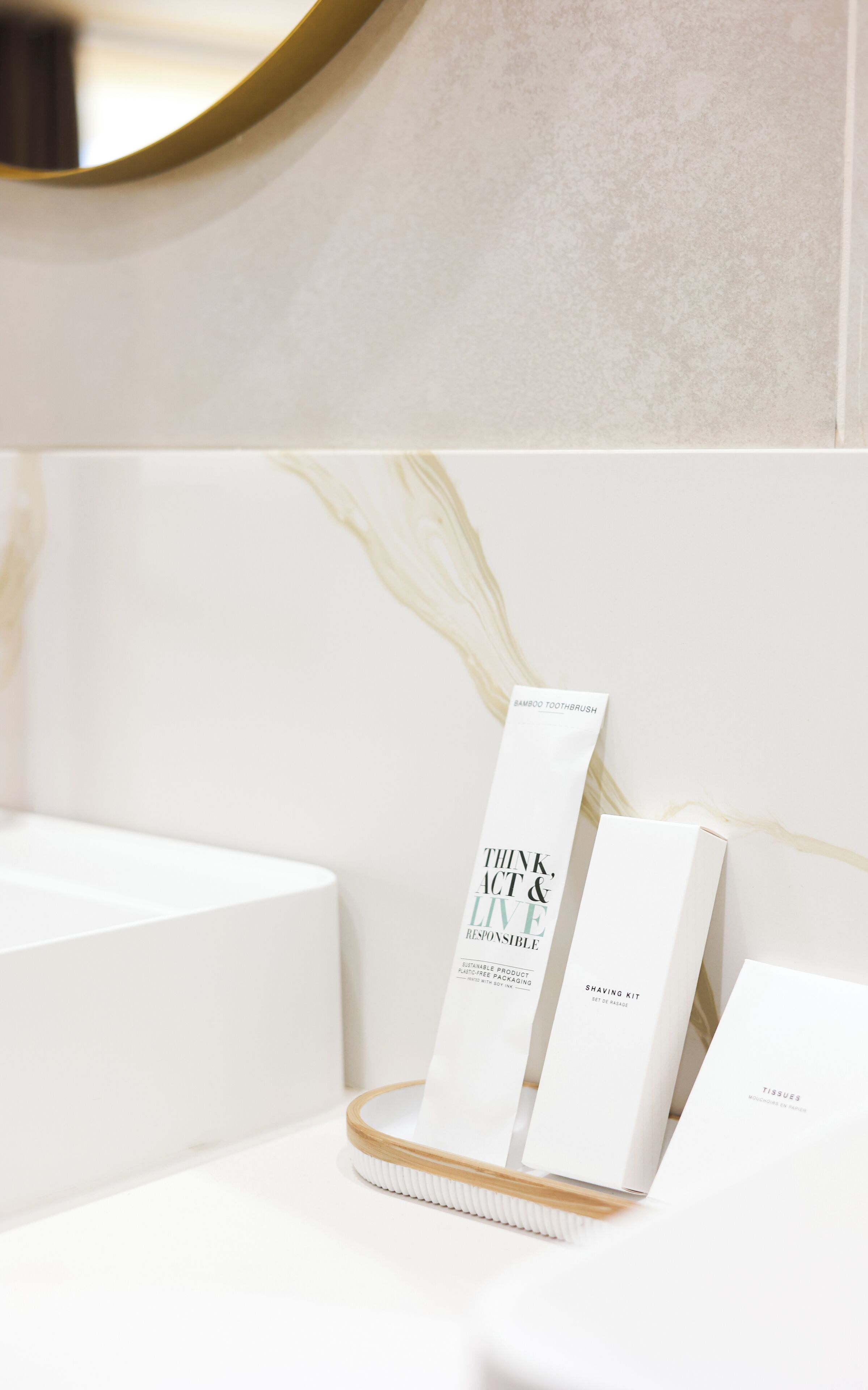 Un baño con un lavamanos blanco, un espejo y un organizador de bambú para cepillos de dientes con un neceser.