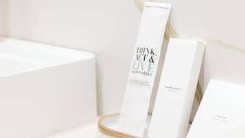 Un baño con un lavamanos blanco, un espejo y un organizador de bambú para cepillos de dientes con un neceser.