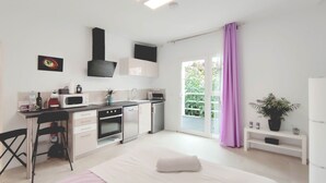 Een moderne keuken met een eethoek, een bed en uitzicht op groen.