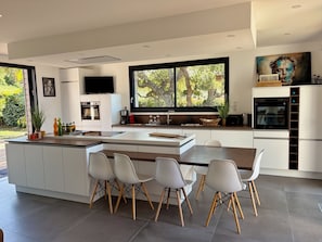 Een moderne keuken met een centraal eiland, witte kasten en een groot raam.