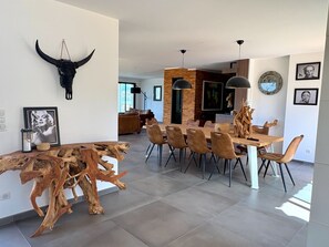 A modern dining area with a wooden table and chairs, a bull skull decoration, and a rustic wooden sculpture. - Superb 14-person villa with sea view and heated pool (Porto-Vecchio)