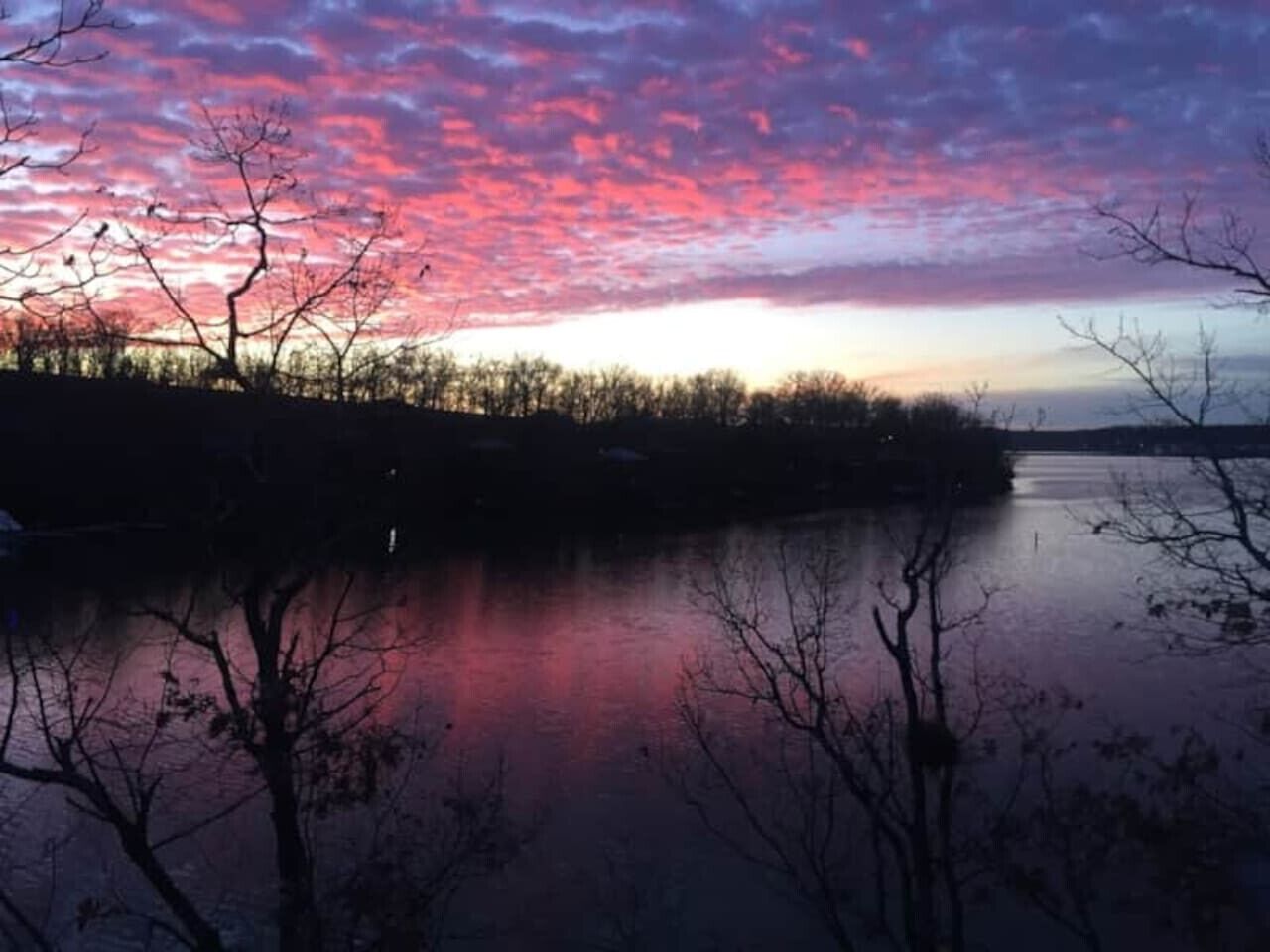 Una vista serena de un lago con un cielo de atardecer reflejado en aguas tranquilas.