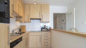 A compact kitchen with wooden cabinets, a built-in oven, and a stainless steel sink. - 3 bedroom accommodation in Sint-Idesbald (Sint-Idesbald)