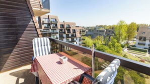 Un balcon avec une nappe à carreaux, une chaise à rayures et un bol blanc.