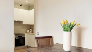 A dining area with a wooden table and a vase of yellow tulips. - Enjoy Apartments Donna (Barcelona)