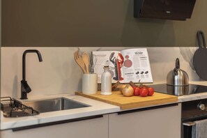 Une cuisine équipée d’un robinet moderne, d’une planche à découper en bois avec des légumes, d’une bouilloire et d’un livre de recettes.