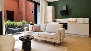 Una sala moderna con un sofá, una mesa de centro y vistas a una cocina y un área de estar al aire libre.