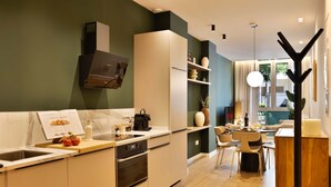 A modern kitchen with a built-in oven, a sink, and a dining area with a table and chairs.