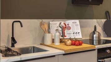 Una cocina con un grifo moderno, una tabla de madera con verduras, un hervidor y un libro de cocina.