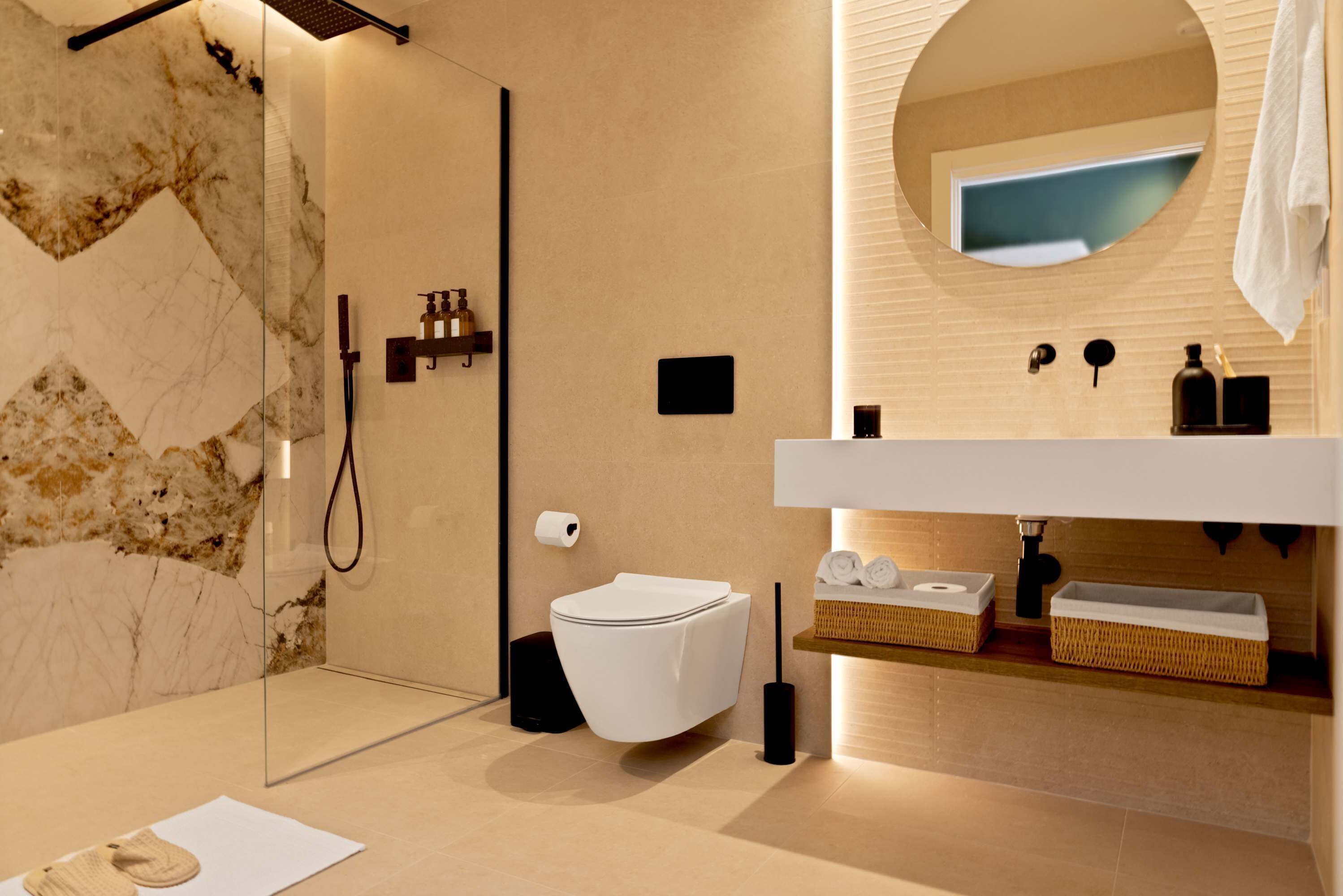 Un baño moderno con cabina de ducha de vidrio, inodoro blanco y tocador con espejo.