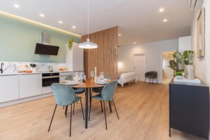 A modern kitchen with a dining area, a TV mounted above the counter, and a wooden partition.